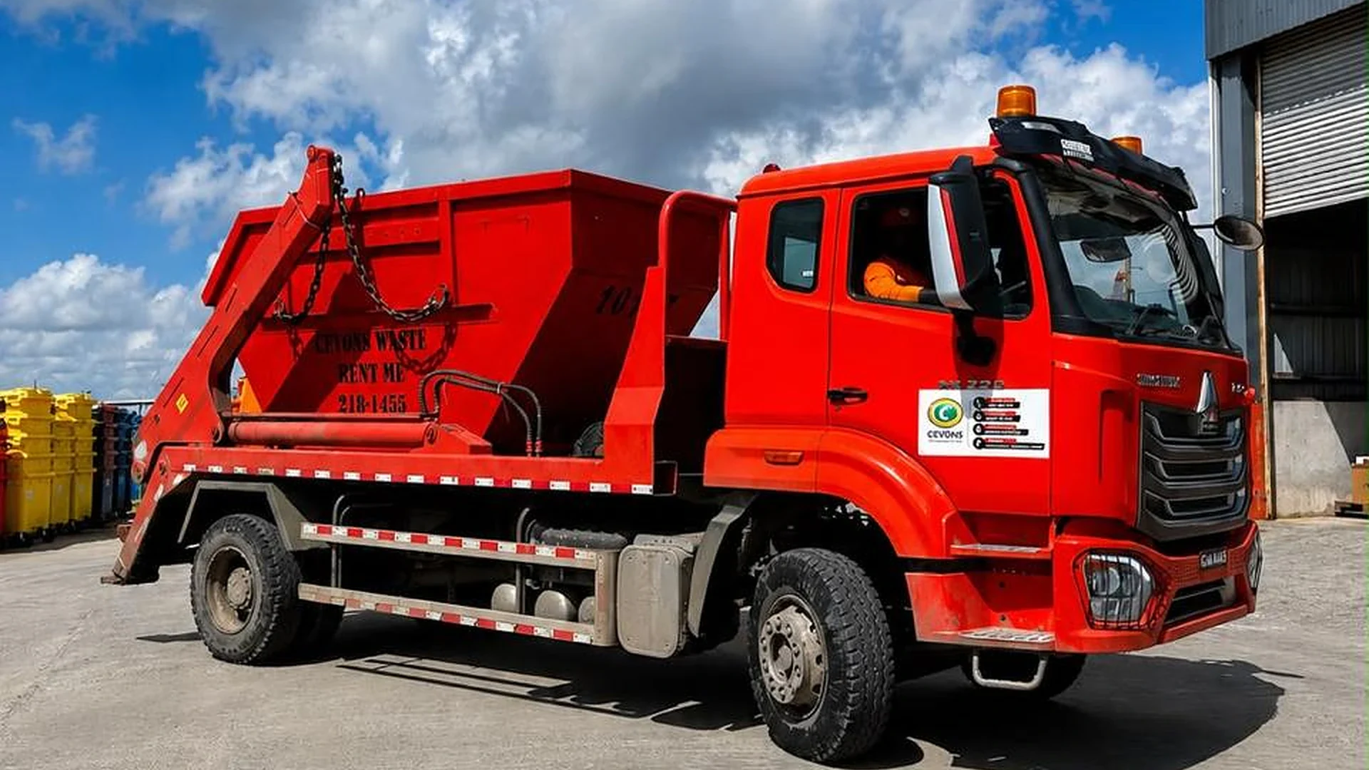 CEVONS red Sinotruk Howo skip bin truck loaded with waste on site in Guyana